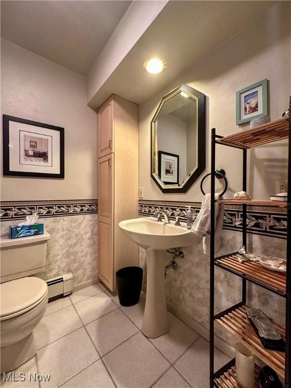 half bath with tile patterned flooring, toilet, baseboard heating, wainscoting, and tile walls