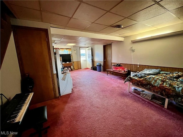 interior space with wooden walls, carpet flooring, a wainscoted wall, and a drop ceiling