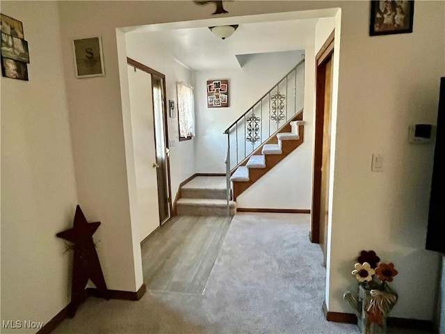 carpeted foyer entrance with baseboards and stairs