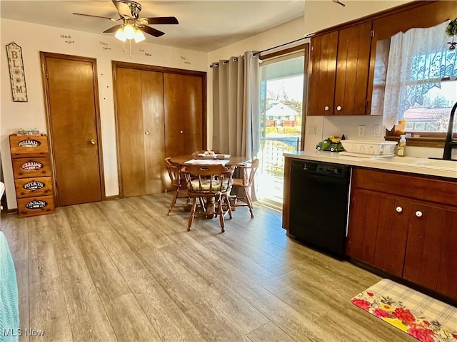 kitchen featuring light wood-style flooring, light countertops, black dishwasher, and a sink