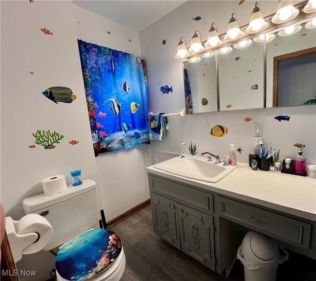 bathroom with baseboards, toilet, wood finished floors, and vanity