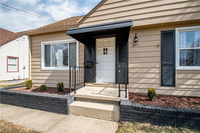 property entrance featuring a shingled roof