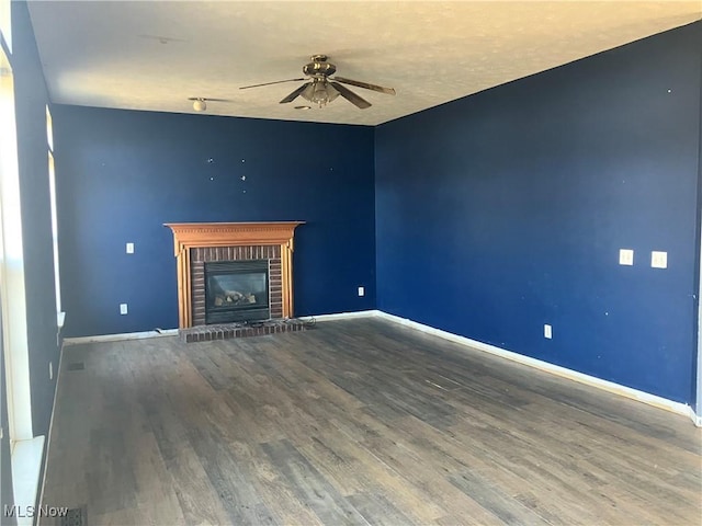 unfurnished living room featuring a fireplace, wood finished floors, baseboards, and ceiling fan