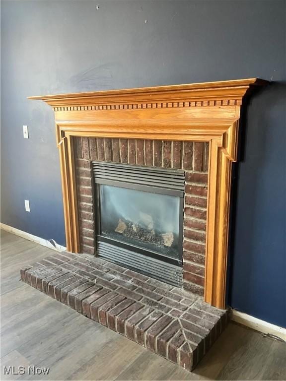 interior details with a brick fireplace, baseboards, and wood finished floors