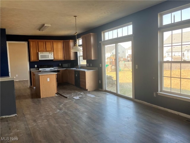 kitchen featuring white microwave, a center island, electric stove, and dark wood-style flooring