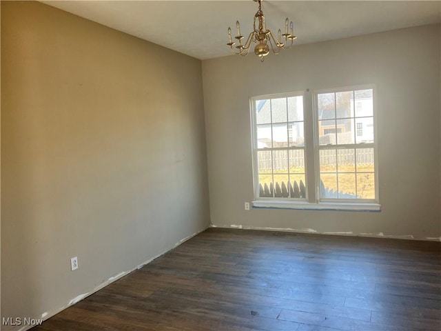 unfurnished room featuring a notable chandelier and dark wood-style flooring