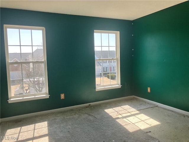 empty room with a wealth of natural light and baseboards