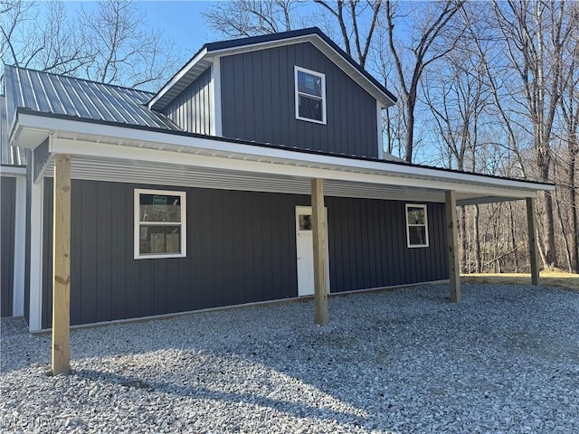 exterior space with metal roof, an attached carport, board and batten siding, and driveway