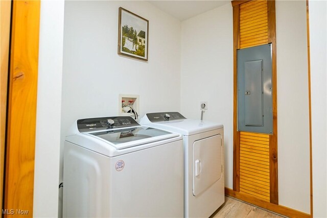 washroom with baseboards, light wood-type flooring, electric panel, laundry area, and independent washer and dryer