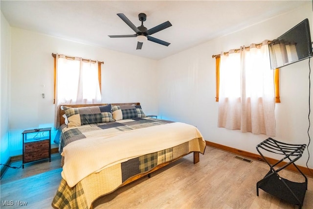 bedroom featuring visible vents, baseboards, wood finished floors, and a ceiling fan