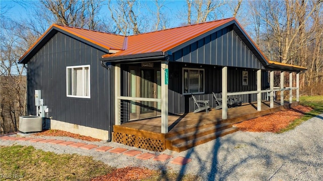 view of front of house with metal roof, board and batten siding, covered porch, crawl space, and central AC unit