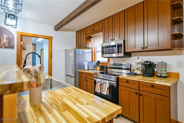 kitchen featuring beam ceiling, open shelves, appliances with stainless steel finishes, and butcher block countertops