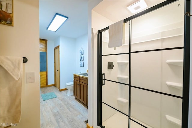 bathroom featuring a shower stall, baseboards, toilet, wood finished floors, and vanity