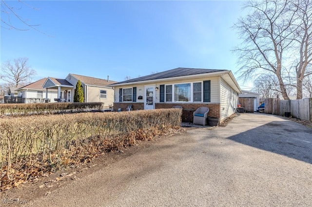 view of front of house with brick siding, driveway, and fence