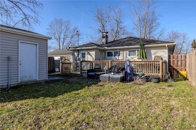 back of house with an outdoor structure, a lawn, a deck, and fence