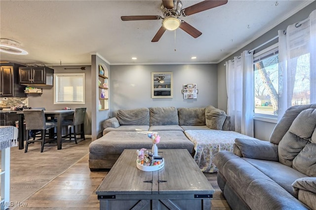 living room featuring light wood-type flooring, recessed lighting, crown molding, baseboards, and ceiling fan