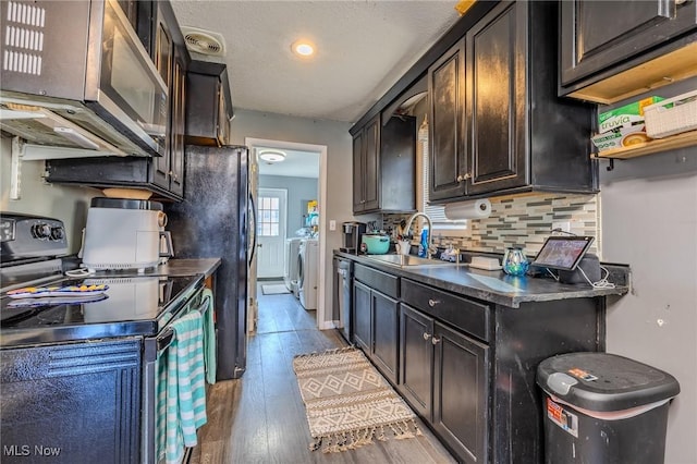 kitchen featuring a sink, dark countertops, tasteful backsplash, wood finished floors, and appliances with stainless steel finishes