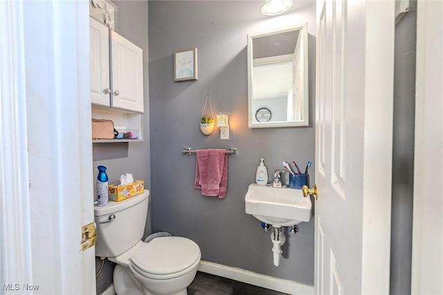 bathroom with toilet, baseboards, and a sink