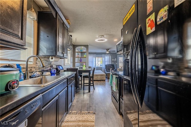 kitchen featuring light wood-type flooring, black appliances, a sink, a textured ceiling, and open floor plan