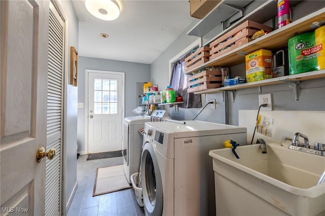 laundry room with laundry area, independent washer and dryer, wood finished floors, and a sink