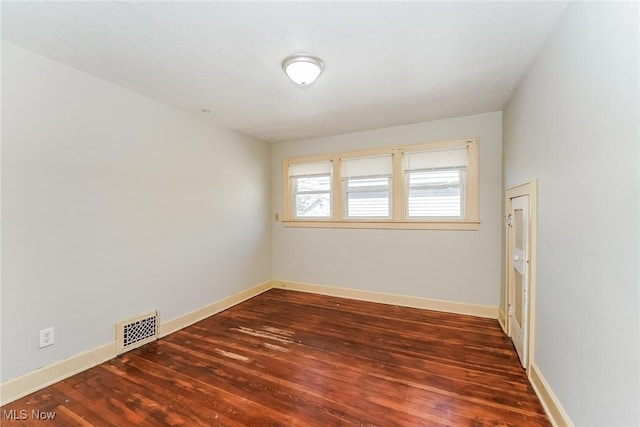 spare room featuring visible vents, baseboards, and wood finished floors