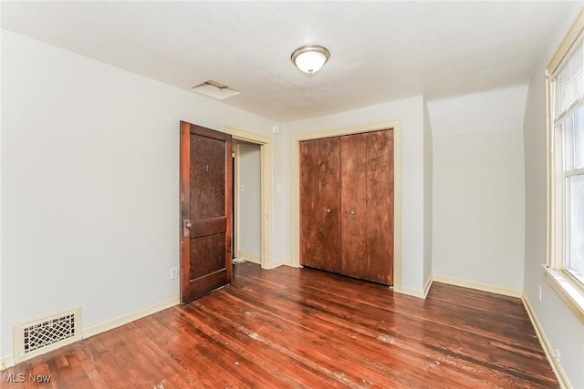 unfurnished bedroom with wood finished floors, visible vents, and baseboards