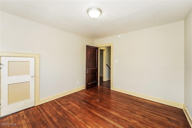 spare room featuring wood finished floors and baseboards