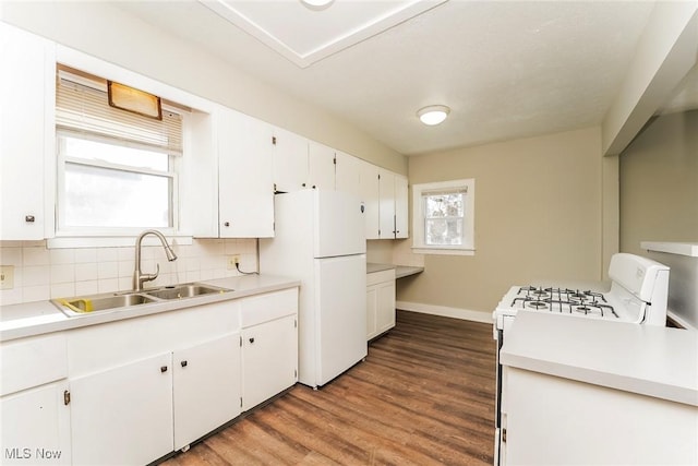 kitchen with a sink, backsplash, wood finished floors, white cabinetry, and white appliances