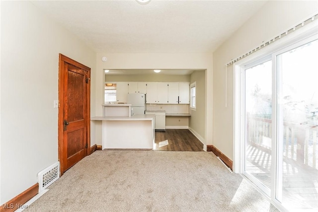 unfurnished living room with dark colored carpet, visible vents, and baseboards