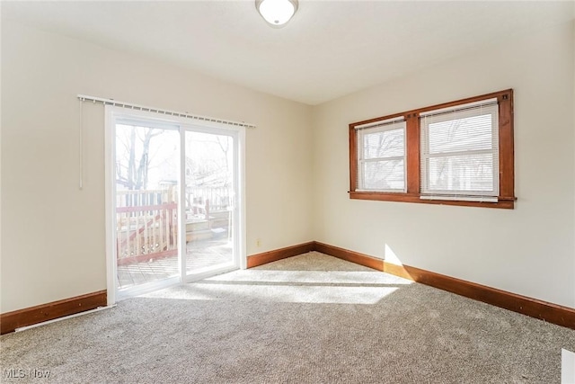 spare room featuring a healthy amount of sunlight, baseboards, and carpet