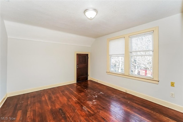 empty room with vaulted ceiling, baseboards, and hardwood / wood-style flooring