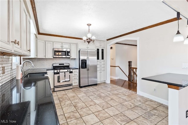 kitchen with ornamental molding, a sink, tasteful backsplash, white cabinetry, and appliances with stainless steel finishes