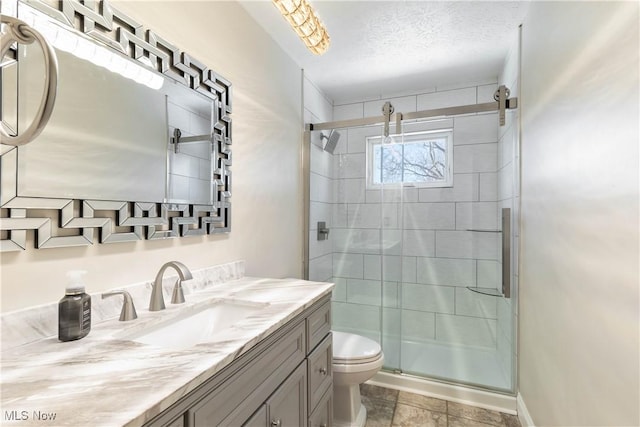 full bath with toilet, a stall shower, a textured ceiling, baseboards, and vanity