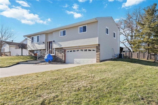 split foyer home featuring a front lawn, an attached garage, fence, and central AC