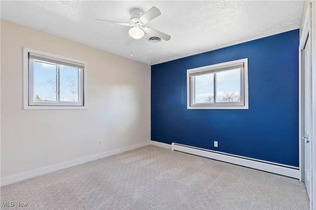 carpeted spare room with visible vents, a ceiling fan, a textured ceiling, baseboards, and baseboard heating