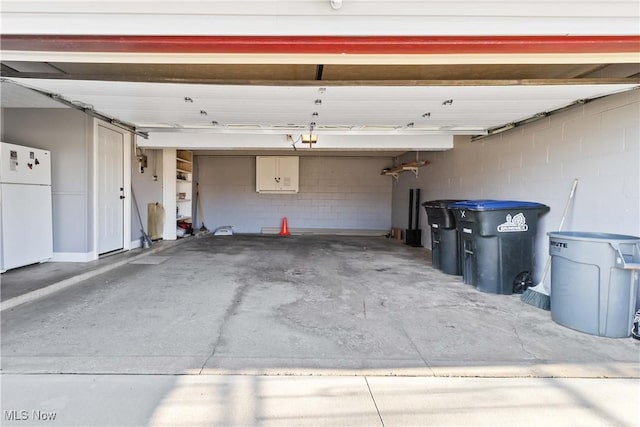 garage featuring concrete block wall and freestanding refrigerator