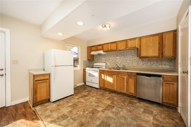 kitchen featuring under cabinet range hood, a sink, white appliances, brown cabinetry, and decorative backsplash