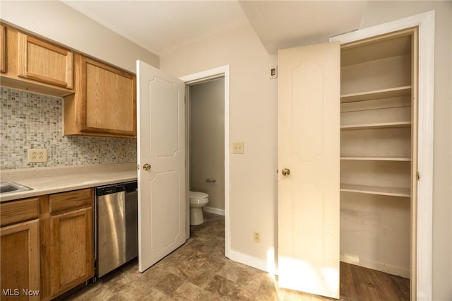 kitchen featuring tasteful backsplash, brown cabinetry, light countertops, baseboards, and dishwasher