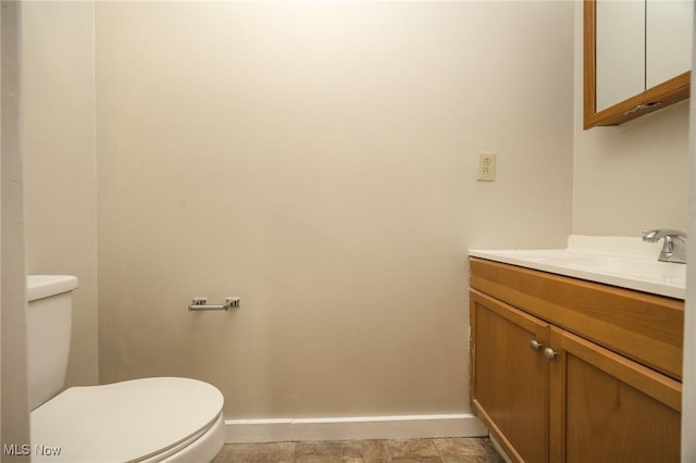 half bath featuring vanity, toilet, and baseboards