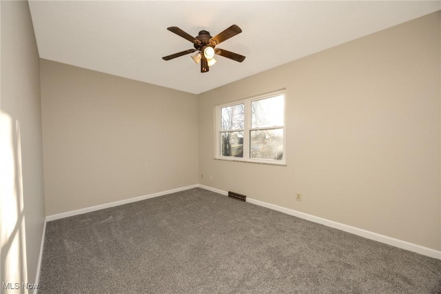 spare room featuring visible vents, a ceiling fan, baseboards, and dark carpet