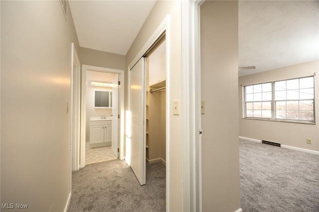 hallway featuring carpet flooring, baseboards, and visible vents