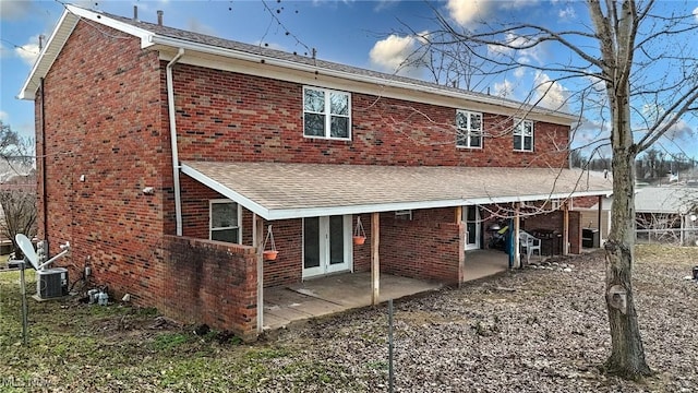 back of house featuring brick siding, a shingled roof, and a patio