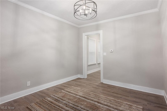 empty room with a notable chandelier, crown molding, baseboards, and wood finished floors