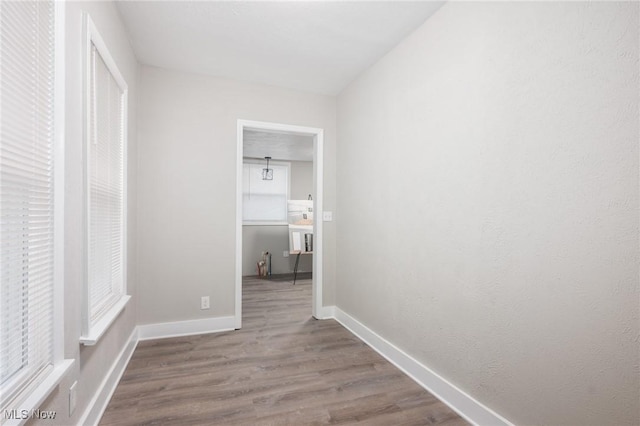 corridor with baseboards and wood finished floors