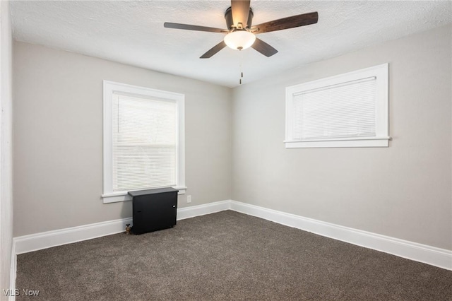 spare room with dark colored carpet, baseboards, a textured ceiling, and ceiling fan