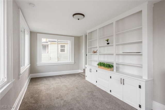 carpeted empty room featuring built in features and baseboards