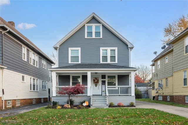 american foursquare style home featuring covered porch and a front lawn