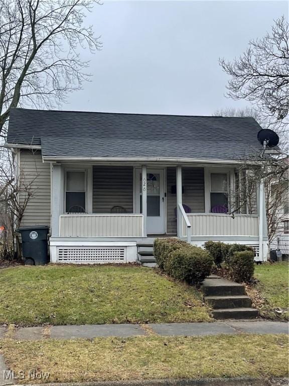 view of front of home featuring a porch, a front lawn, and a shingled roof