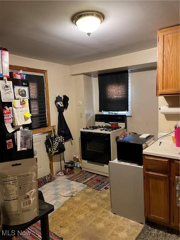 kitchen with white gas stove and light countertops