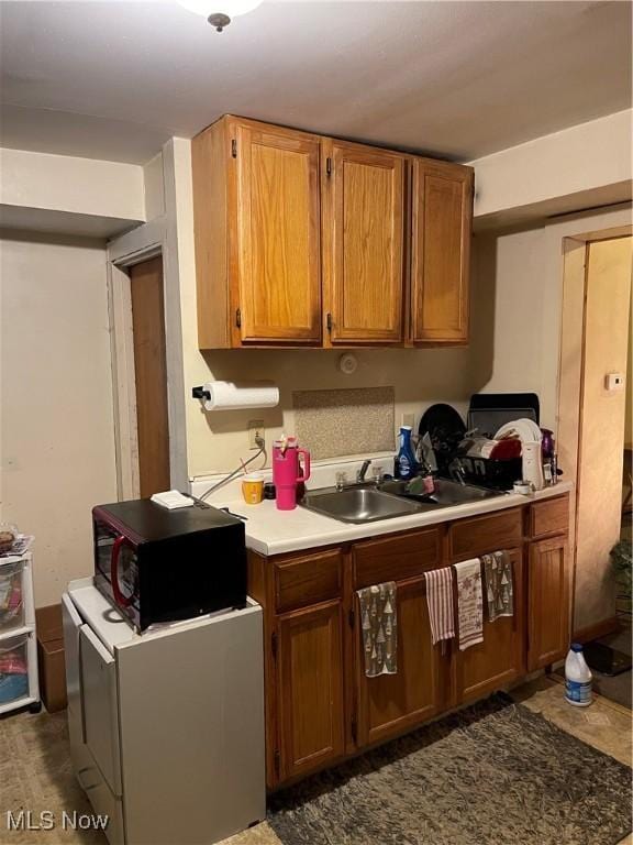 kitchen featuring light countertops, brown cabinetry, and black microwave